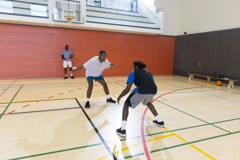 African american men practicing one-on-one basketball on indoor hardwood court playing defense and o
