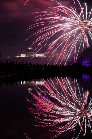 Vibrant Fireworks Reflecting Over Tranquil Water During Festival