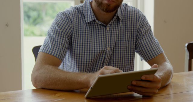 Man with Checked Shirt Using Tablet at Wooden Table - Download Free Stock Images Pikwizard.com