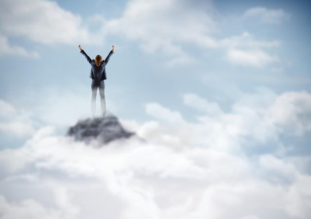 Digital composite of Business woman cheering on mountain peak in the clouds