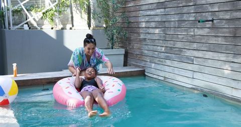 Mother and Daughter Enjoy Summer Weather at Poolside On Inflatable