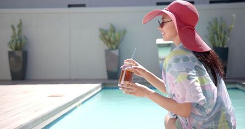 Woman Relaxing Poolside with Iced Tea and Sun Hat on Sunny Day