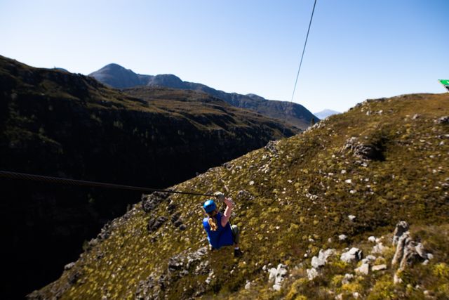 Woman Zip Lining Over Mountainous Landscape on Sunny Day - Download Free Stock Photos Pikwizard.com