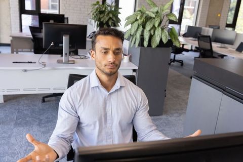 Confused Professional Reviewing Monitor in Modern Office Space