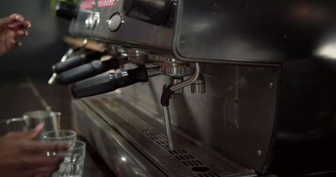 African american barista preparing espresso with steam wand on cafe counter