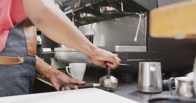 Biracial female barista wearing apron preparing coffee with coffee machine in cafe - Download Free Stock Photos Pikwizard.com
