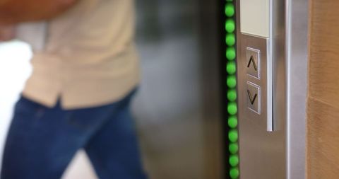 Elevator Buttons Pressed by Business Professional with Documents