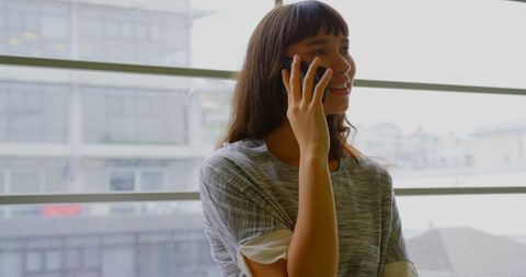Businesswoman Talking on Smartphone by Office Window, Urban Background