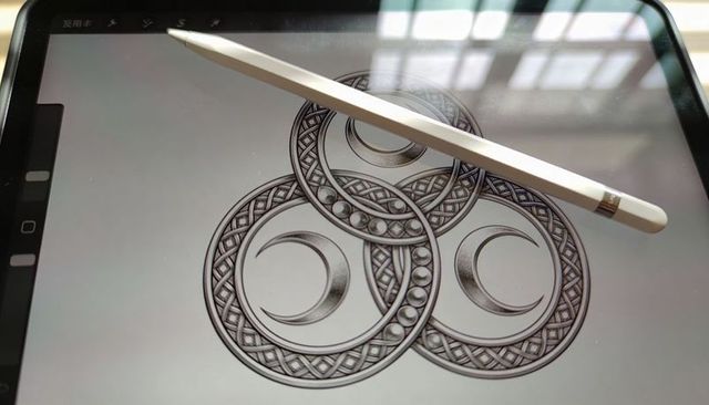 Digital stylus resting on tablet displaying intricate celtic knotwork triple moon line art