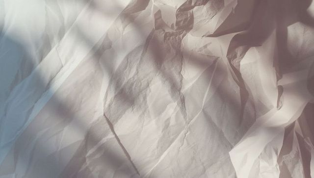Crumpled white sheet lit by natural shadows