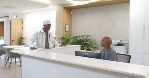 African-american doctor consulting with receptionist, collaborating at modern clinic desk