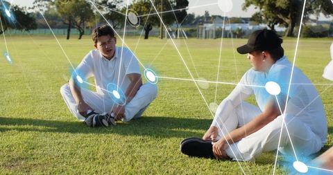 Teenage cricketers stretching and talking on grass pitch with digital network overlay