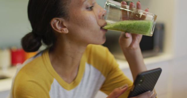 Woman Drinking Green Smoothie while Using Smartphone in Kitchen - Download Free Stock Images Pikwizard.com