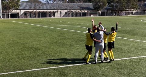 Diverse Soccer Players Celebrating on Field in Yellow and Black Uniforms