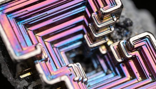 Iridescent bismuth hopper crystal macro showcasing geometric terraces and rainbow sheen