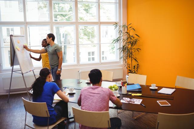 Business team collaborating during an office meeting. Ideal for illustrating teamwork, professional environments, corporate strategy sessions, and collaborative workspaces.