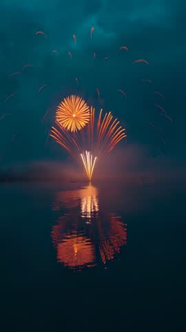 Bursting golden fireworks reflecting on calm lake vertical video for celebrations