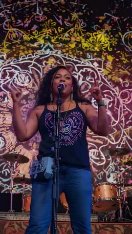 Vertical lead singer performing with psychedelic visuals and vibrant stage lighting