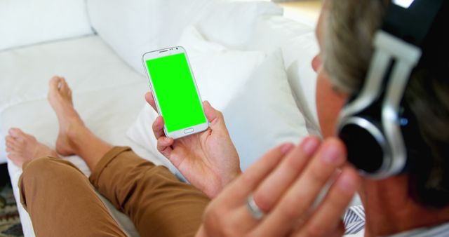 Man Relaxing on Couch with Headphones and Smartphone with Green Screen - Download Free Stock Images Pikwizard.com