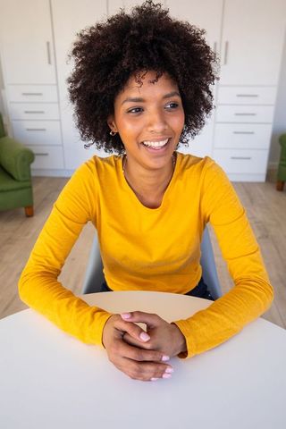 Smiling Woman in Yellow Shirt at Home Approaching Relaxation