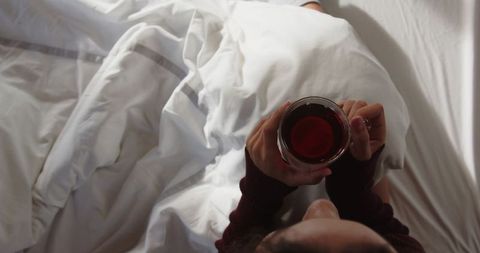 Woman relaxing in bed with red tea on cozy morning