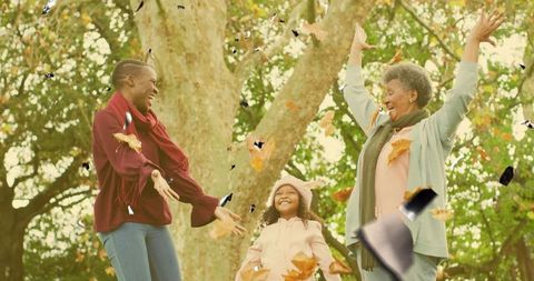 Three-Generation Family Tossing Leaves in Autumn Park Celebrating Joy and Togetherness