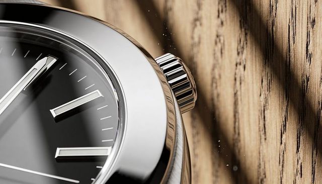Macro closeup stainless steel watch bezel and ridged crown meeting domed crystal on wood