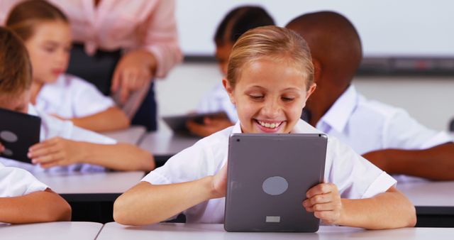 Happy schoolchildren using digital tablets in classroom - Download Free Stock Images Pikwizard.com