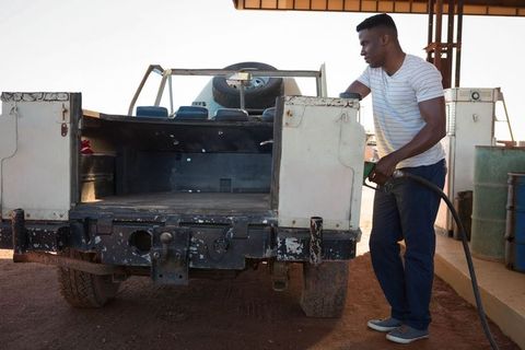 African american man refueling pickup truck with spare tire at rural station