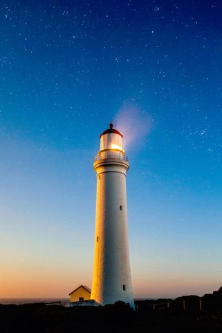 Lighthouse illuminated against a starry night sky
