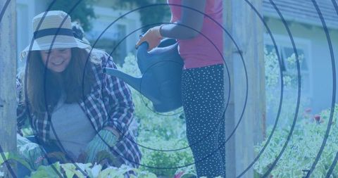 Multigenerational family gardening planting and watering raised bed with child pouring