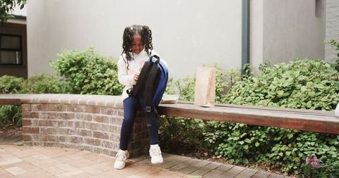 Schoolgirl Sitting on Bench Ready for Snack Time Outdoors