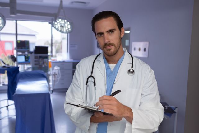 Male doctor writing on clipboard in a hospital operation room. Ideal for healthcare, medical, and hospital-related content. Can be used for articles, blogs, or advertisements focusing on medical professionals, hospital environments, or healthcare services.
