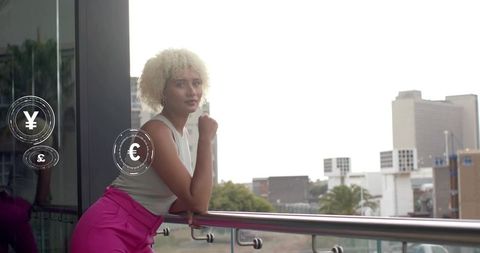 Young professional woman leaning on balcony analyzing currency icons with skyline