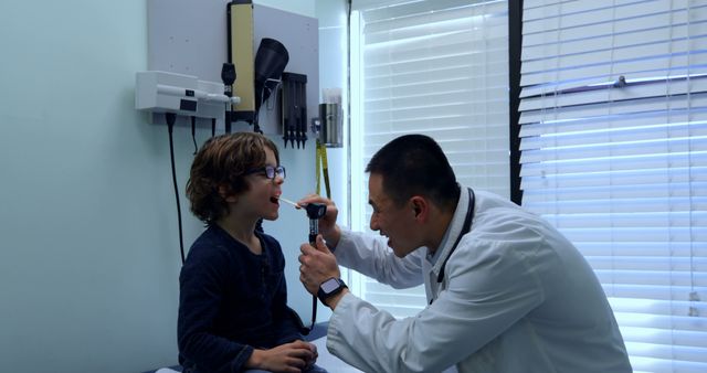 Pediatrician examining young boy with otoscope during check-up - Download Free Stock Images Pikwizard.com