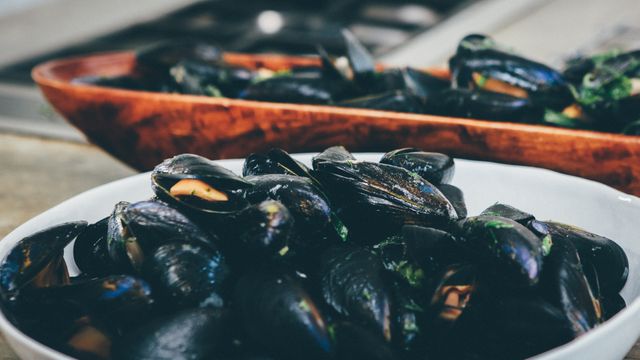 Delicious freshly cooked mussels in bowls placed on kitchen counter. Great for images related to seafood recipes, culinary delights, restaurant promotions, or cooking blogs. Highlights appetizing and nutritious shellfish ideal for gourmet dining.