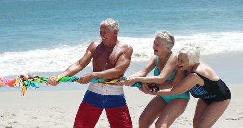 Senior Friends Enjoying Beach Tug-of-War