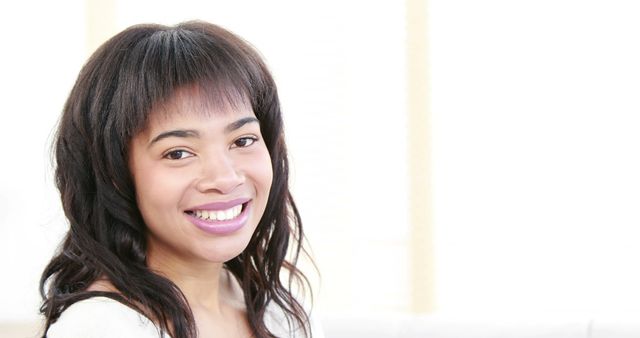 This image features a smiling woman with curly hair posing against a bright white background. Her expression and posture suggest confidence and positivity. Ideal for use in advertisements, websites, blogs, and articles focused on positivity, happiness, self-esteem, and lifestyle.