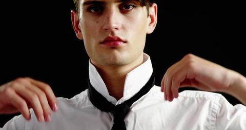 Young Man Adjusting Tie on Black Background - Download Free Stock Images Pikwizard.com