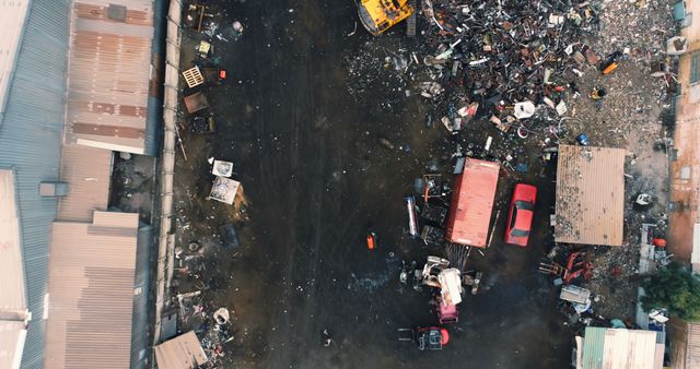 Aerial view showcasing an industrial scrapyard with scattered metal debris, rusty vehicles, and heavy machinery. Useful for topics related to recycling, waste management, environmental conservation, industrial landscapes, and urban development.