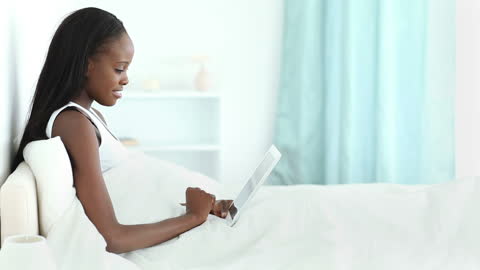 Woman Relaxing in Bed with Tablet Smiling