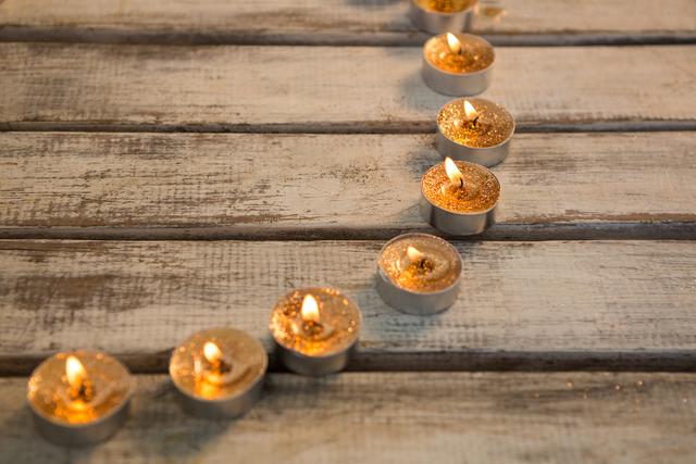 Burning candles arranged on a rustic wooden plank, creating a warm and festive ambiance during Christmas. Ideal for holiday greeting cards, festive decorations, and cozy home decor inspirations.
