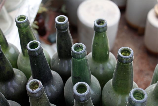Group of empty green glass bottles top view arranged closely together. Use for topics on recycling, environmental conservation, sustainability, and eco-friendly practices.