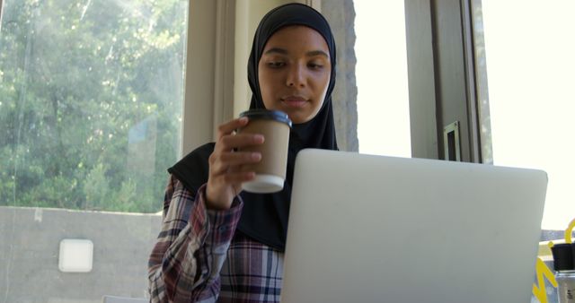 Young Woman in Hijab Working on Laptop Drinking Coffee - Download Free Stock Images Pikwizard.com