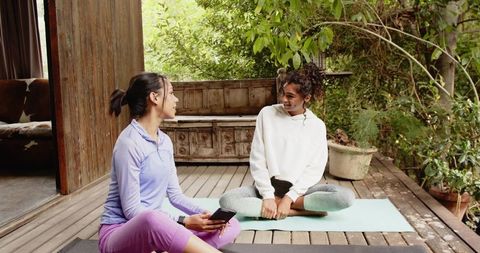 Friends relaxing on yoga mats engaged in conversation