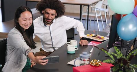 Coworkers enjoying office celebration and taking selfie