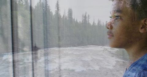 Boy gazing through window at rushing river double exposure contemplative forest portrait