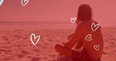 Man meditating on beach surrounded by heart doodles