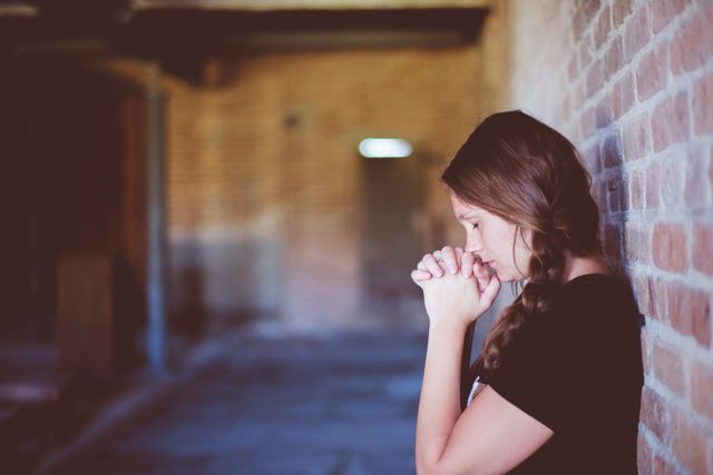 Young Woman Praying in Quiet Corridor - Download Free Stock Photos Pikwizard.com