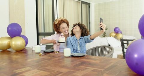 African American friends celebrating birthday taking selfie with cake and purple balloons